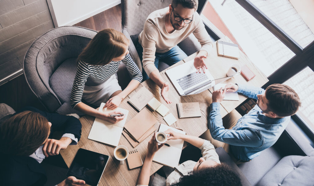 Business meeting. Top view of buiness team brainstorming while sitting at the office table together
