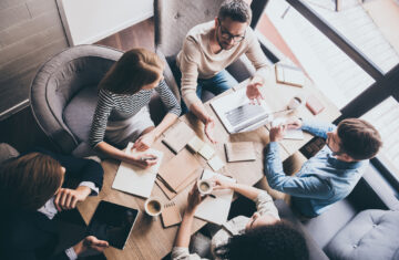 Business meeting. Top view of buiness team brainstorming while sitting at the office table together